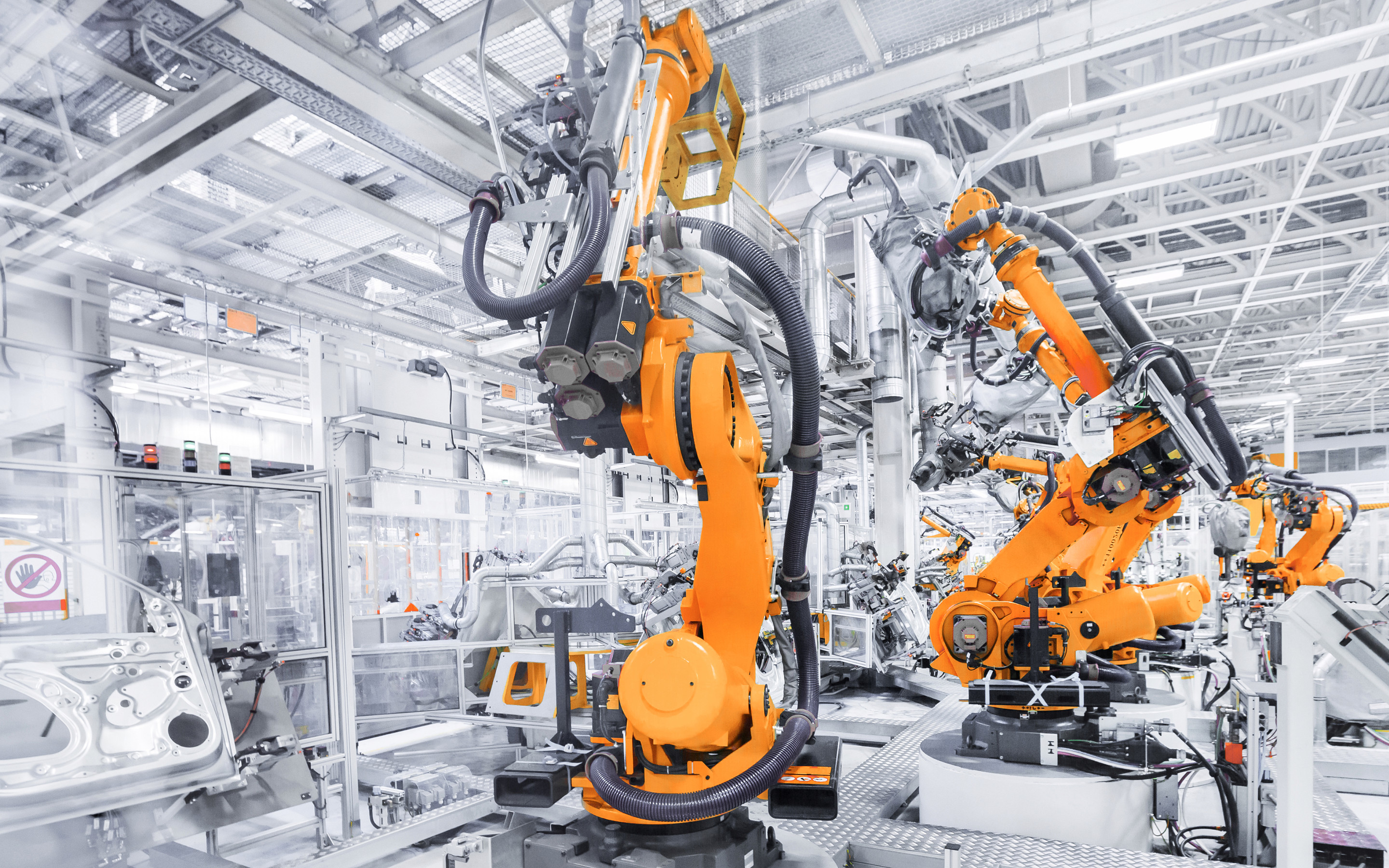Orange industrial robot arms on an automated assembly line